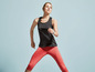 Eine Frau in einem schwarzen Sporttop und roten Leggings beim Training