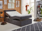 Ein elektrisch verstellbares Bett mit Stauraum und grauem Bezug.