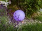 Eine lila Lampe in einem Garten mit Lavendel.