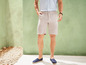 Mann mit beigen Shorts und blauen Espadrilles.