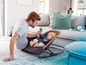 Ein Vater spielt mit seinem Baby in einem BabyBjörn Bouncer.