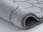 Ein grauer Badeteppich mit geometrischem Muster.