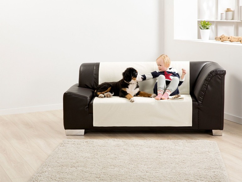 Ein Kind und ein Hund auf einem braunen Ledersofa mit einer weißen Schutzhülle.