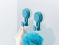 Zwei blaue Haken mit Saugnäpfen in der Dusche, mit einem Handtuch und einem Schwamm