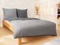 Ein grauer Bettbezug auf einem Holzbett.