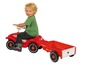Ein Kind fährt auf einem roten Bobby Car mit Anhänger.