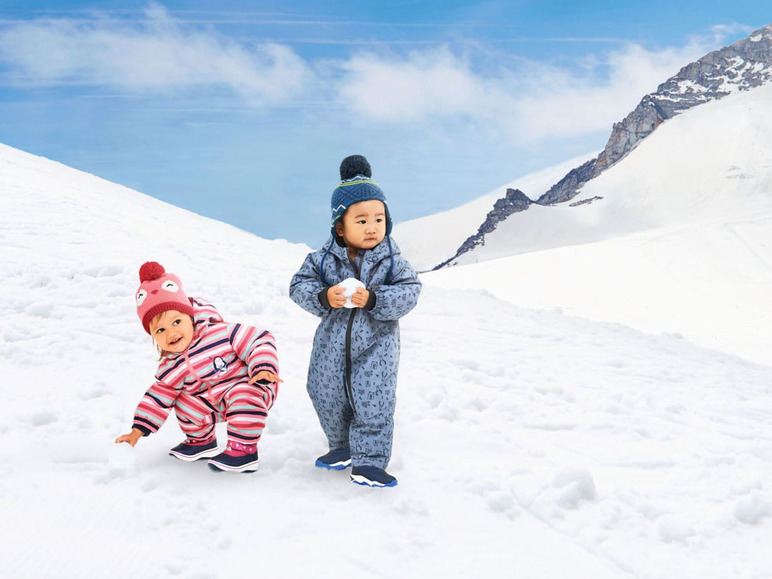 Zwei Babys in Winterkleidung spielen im Schnee.