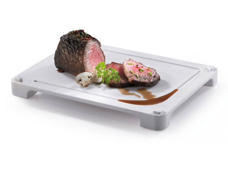 Gegrilltes Steak mit Champignons auf einem weißen Schneidebrett mit Füßen.