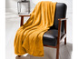 Eine gelbe Decke auf einem schwarzen Stuhl.
