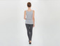Frau in einem grauen Tanktop und schwarzen Leggings.