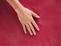 Eine Hand auf einem roten, gewebten Untergrund.