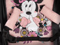 Ein rosa Kinderwagen mit Minnie Mouse-Druck und rosa Armlehnen.