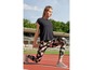 Frau in schwarzem Oberteil und bedruckten Leggings beim Dehnen auf einer Laufbahn.
