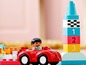 Ein rotes Auto mit einer LEGO Duplo Figur neben einem Turm mit Zahlenblöcken.