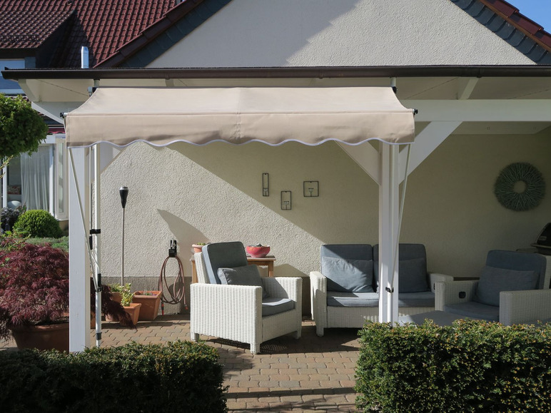 Weiße  Gartenstühle aus  Weide unter  einem  beigen Sonnenschirm.