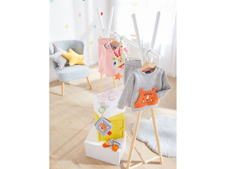 Babykleidung mit Tiger-Druck auf einem Holzständer.