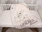 Eine beige Babydecke mit einem Teddybären und einem Lamm, mit dem Schriftzug 'Kleiner Liebling Mensch'.