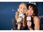 Zwei Frauen singen Karaoke mit tragbaren Lenco-Mikrofonen.
