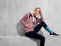 Frau trägt einen rosa Hoodie und schwarze Leggings.