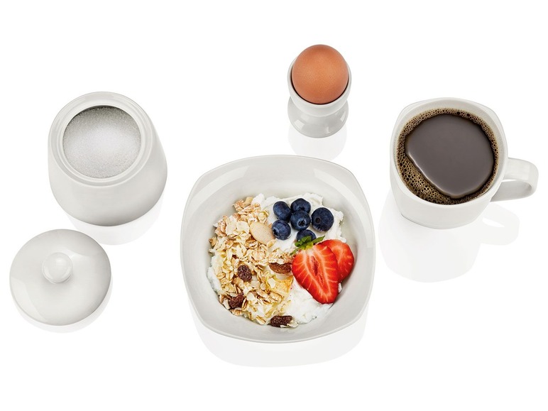 Frühstück mit Joghurt, Müsli, Beeren und Erdbeeren, Kaffee und einem gekochten Ei.