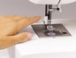 Eine Hand bedient eine Nähmaschine.