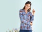 Eine Frau trägt eine blaue Bluse mit Blumenmuster.