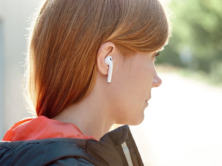Eine Frau mit roten Haaren trägt weiße drahtlose AirPods.