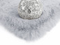 Ein silbergrauer Plüschteppich mit einer Glasdekoration.