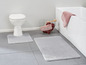Zwei Badezimmermatten und eine Toilette in einem Badezimmer.