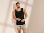 Mann in einem schwarzen Tanktop und grauen Boxershorts.
