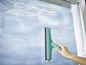 Ein grüner Leifheit Fensterwischer wird zum Reinigen eines Fensters verwendet.
