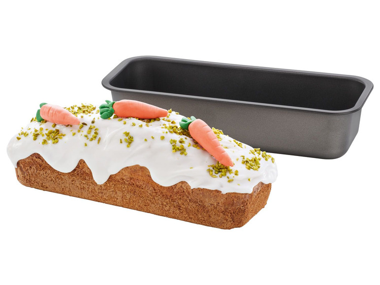 Ein Karottenkuchen mit Zuckerguss und Pistazien in einer Backform.