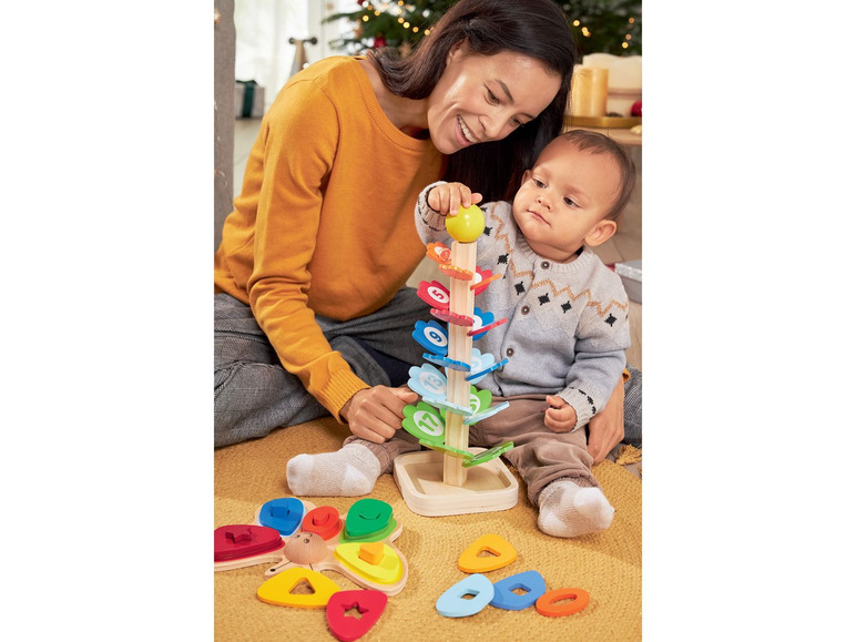 Eine Mutter und ihr Kind spielen mit einem Holzspielzeugbaum mit Zahlen und einem Schmetterlingsspielzeug.