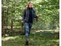 Eine Frau wandert im Wald mit Wanderstöcken und trägt Tarnleggings.