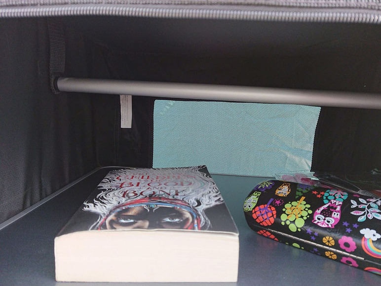 Ein Buch, ein Etui und eine Kleiderstange in einer Aufbewahrungstasche.