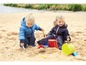 Zwei Kinder spielen mit Schaufeln und Eimern im Sand.