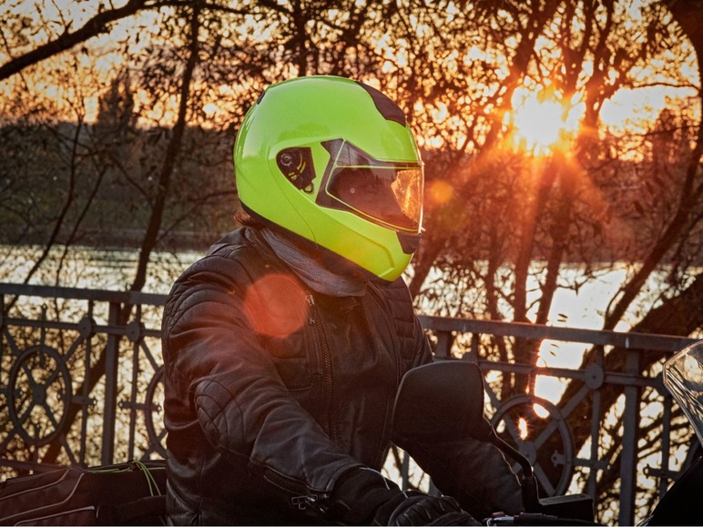 Ein Motorradfahrer mit einem gelben Helm auf einem Motorrad.