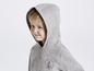 Ein Junge trägt eine graue Kapuzenjacke mit Anker-Motiv.