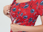 Eine Frau in einem roten Kleid mit Blumenmuster, die das Kleid öffnet, um zu stillen.