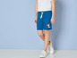 Ein Kind trägt blaue Shorts mit einem Paw Patrol-Aufdruck und weiße Sneaker.