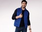 Mann trägt eine blaue Steppweste und einen schwarzen Pullover.