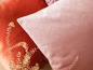 Ein rosa Kissen mit geometrischem Muster und ein orangefarbenes Kissen.