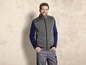 Mann trägt eine graue, mit Reißverschluss geschlossene Weste und einen blauen Pullover.