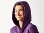 Eine Frau lächelt in einem lila Hoodie.