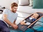 Ein Vater schaut auf sein Baby, das in einem BabyBjörn-Bouncer sitzt.