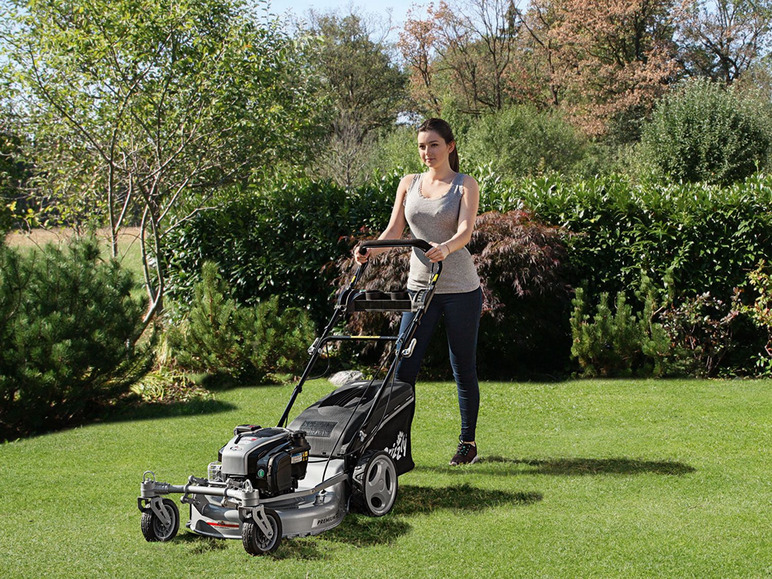 Eine Frau mäht den Rasen mit einem Benzinmäher.