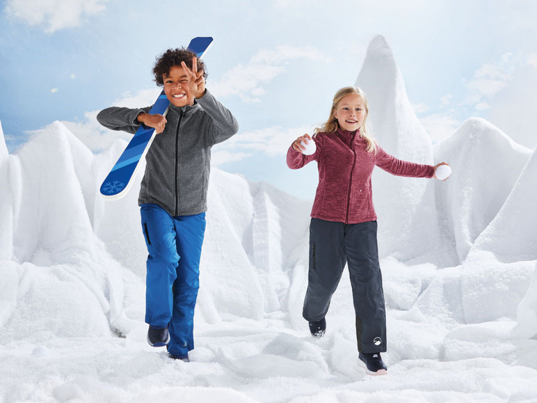 Zwei Kinder spielen im Schnee, eines mit einem Ski und das andere wirft Schneebälle.