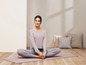 Eine Frau in Sportkleidung sitzt auf einer Yogamatte.