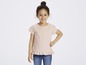 Ein Mädchen trägt ein rosa T-Shirt mit Rüschen und Jeans.