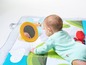 Ein Baby liegt auf einer Spielmatte mit einem Spiegel und anderem Spielzeug.